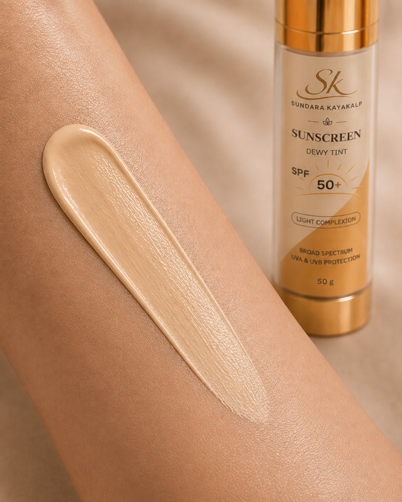 A close-up of a person's forearm with a swatch of beige sunscreen tint applied, next to the Sundara Bayakalp SK Sunscreen Light Complexion Tint SPF 50+ bottle.